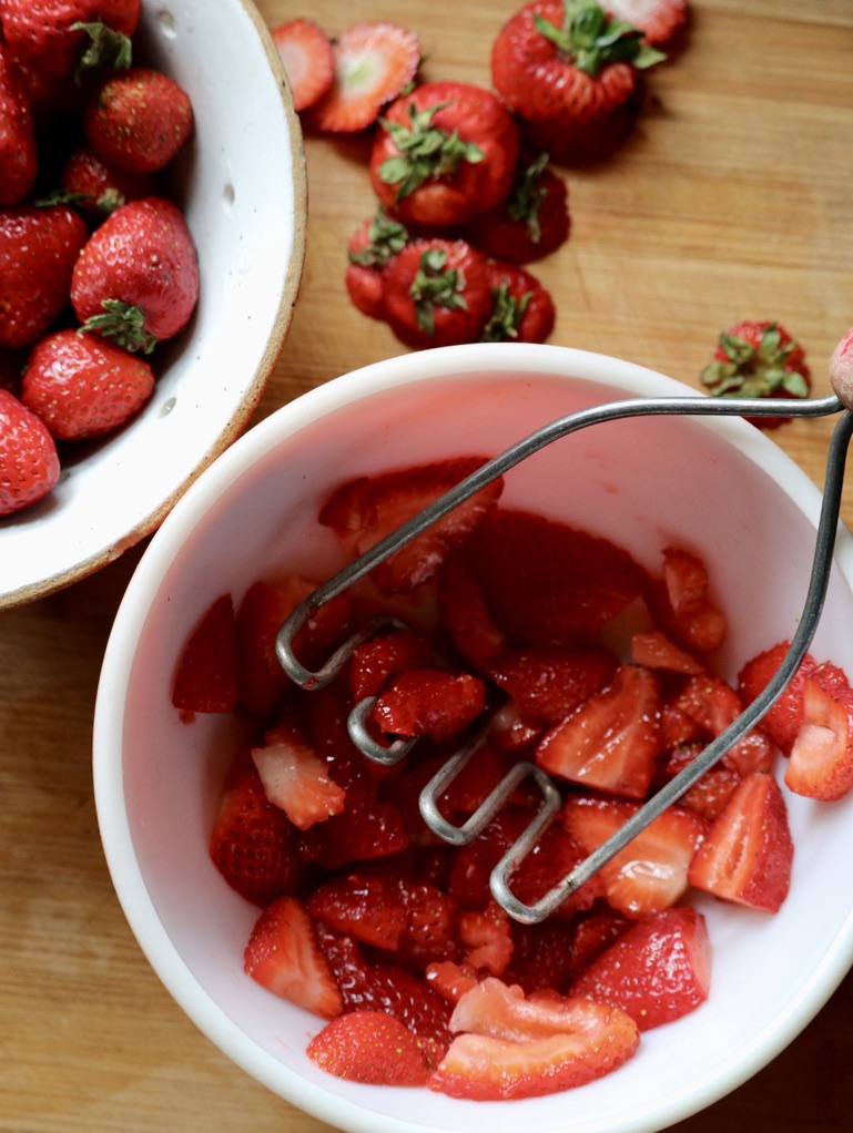 Making strawberry shortcake and crushing strawberries